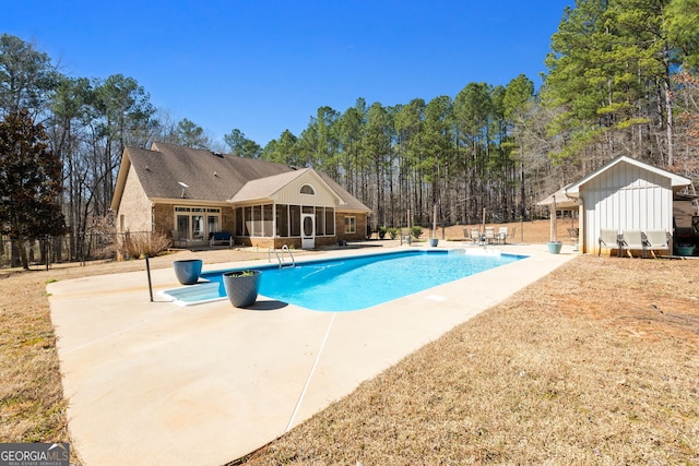 view of swimming pool with a fenced in pool, a sunroom, fence, an outdoor structure, and a patio area