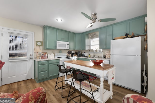 kitchen featuring light countertops, white appliances, a sink, and light wood-style floors