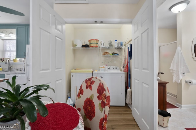 clothes washing area with laundry area, washer and clothes dryer, and light wood-type flooring