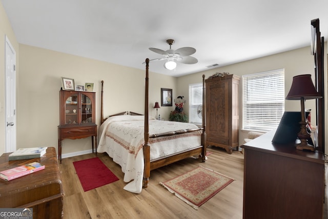 bedroom featuring light wood-style floors, ceiling fan, visible vents, and baseboards