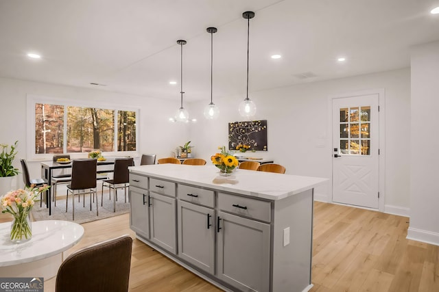 kitchen featuring light wood-style floors, a center island, gray cabinets, and visible vents