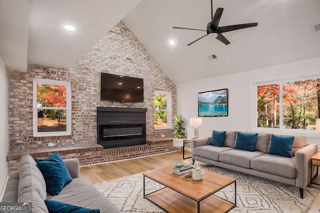 living room featuring ceiling fan, a fireplace, wood finished floors, and visible vents