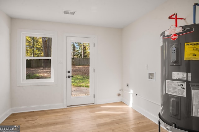 entryway with light wood-style flooring, electric water heater, visible vents, and baseboards