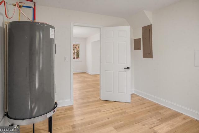 interior space with electric panel, light wood finished floors, water heater, and baseboards