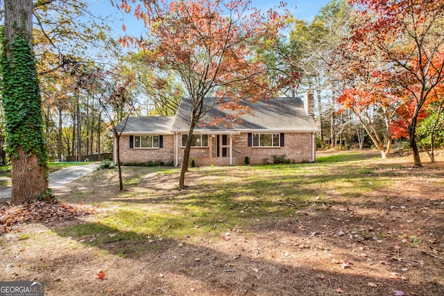 view of front of property with brick siding, a chimney, and a front lawn