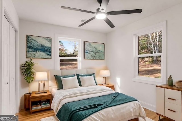 bedroom featuring multiple windows, light wood-type flooring, a closet, and visible vents