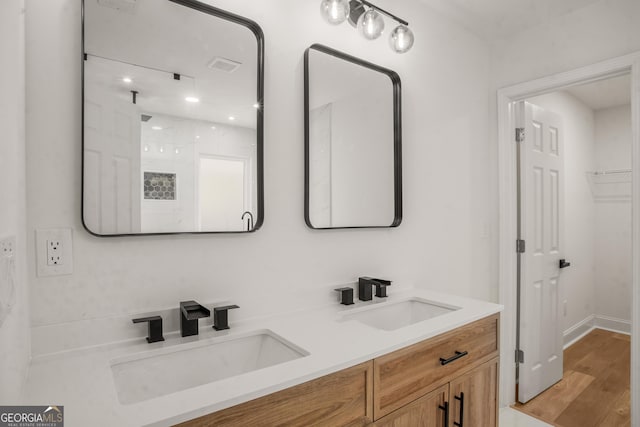 bathroom with double vanity, wood finished floors, a sink, and visible vents