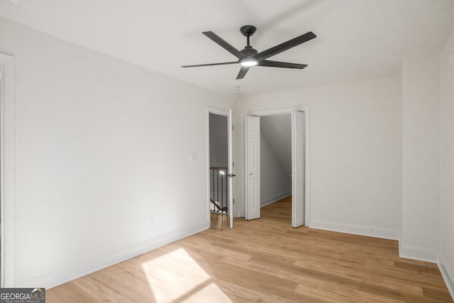 empty room with ceiling fan, light wood-type flooring, and baseboards