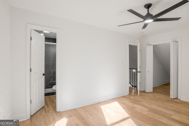 unfurnished bedroom featuring ceiling fan, baseboards, a closet, light wood-type flooring, and a walk in closet