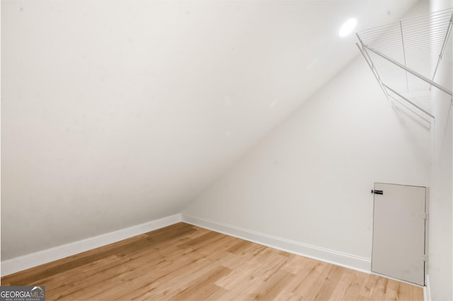 additional living space with light wood-style floors, baseboards, and vaulted ceiling