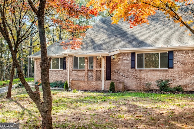 view of front of property featuring brick siding and roof with shingles