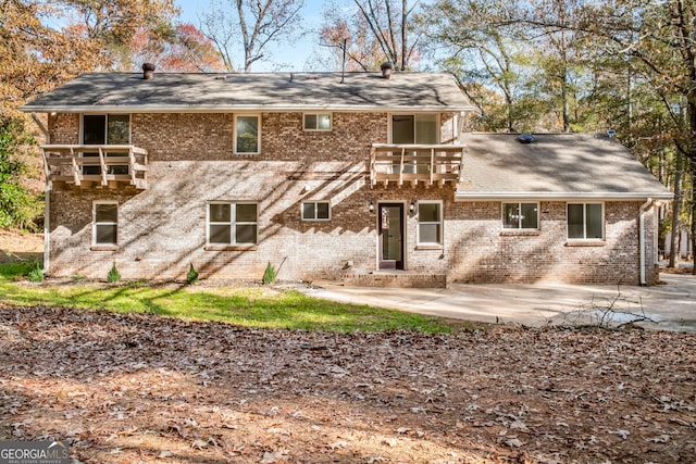 back of property featuring a patio area, brick siding, and a balcony