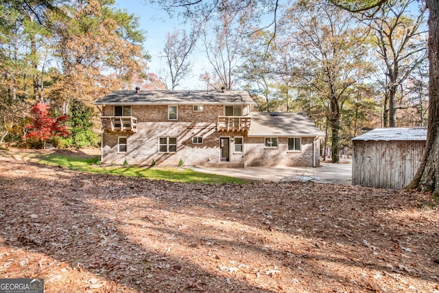 rear view of house featuring a patio, brick siding, and a balcony