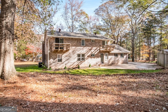 rear view of house with a patio, brick siding, and a balcony