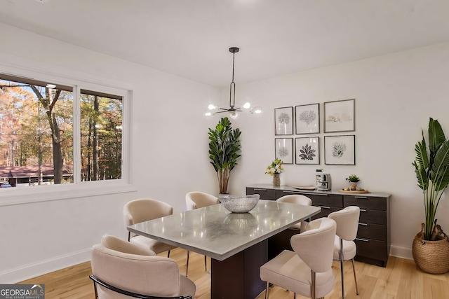 dining area featuring a chandelier, light wood-type flooring, and baseboards