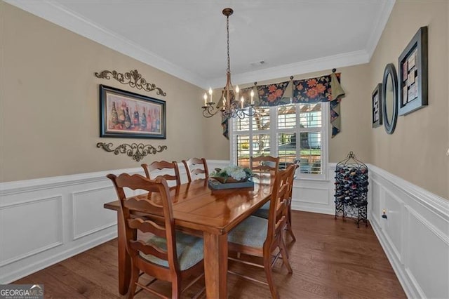 dining room featuring dark wood-type flooring, a chandelier, a wainscoted wall, and crown molding