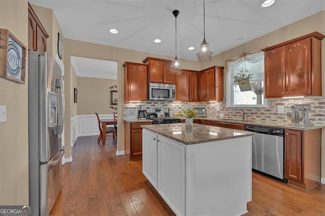 kitchen featuring stone countertops, stainless steel appliances, a sink, wood finished floors, and decorative backsplash