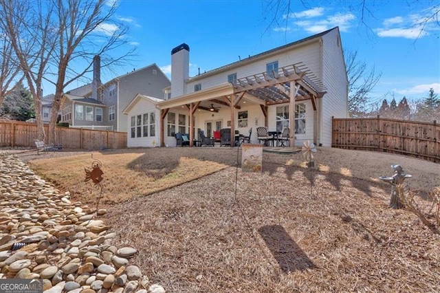 back of house with a ceiling fan, a fenced backyard, a chimney, a patio area, and a pergola