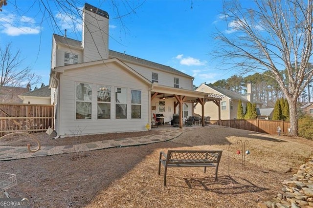 back of house featuring a chimney, fence, and a patio