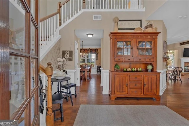 entryway featuring a notable chandelier, a fireplace, wood finished floors, visible vents, and stairway