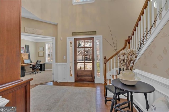 entrance foyer featuring a wainscoted wall, stairway, and wood finished floors