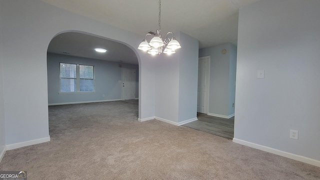 unfurnished dining area featuring carpet floors, arched walkways, a notable chandelier, and baseboards