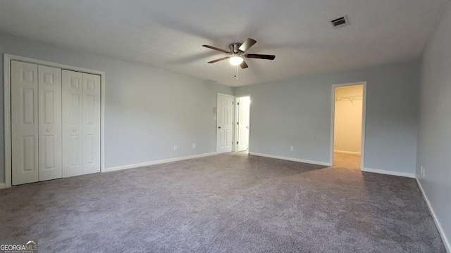 unfurnished bedroom with carpet floors, a closet, visible vents, a ceiling fan, and baseboards