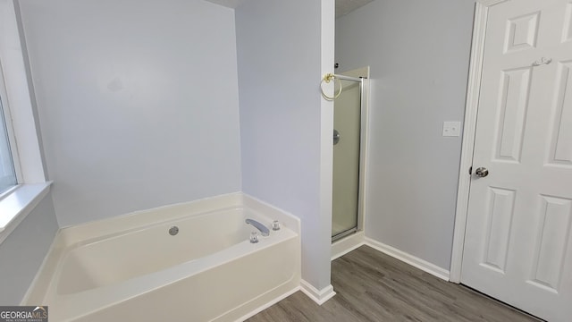 full bathroom featuring wood finished floors, a shower stall, baseboards, and a bath