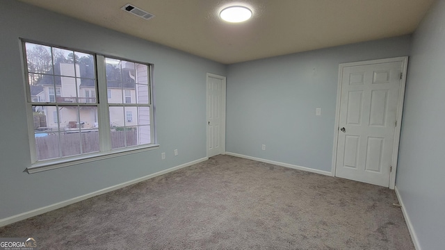 carpeted spare room with plenty of natural light, visible vents, and baseboards