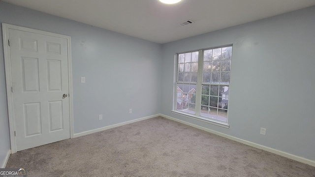 carpeted empty room with visible vents and baseboards