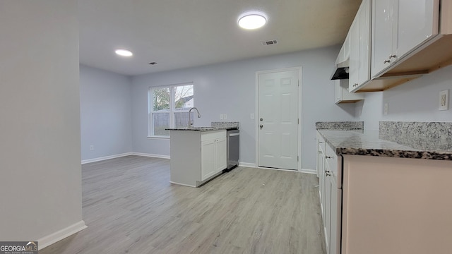 kitchen featuring visible vents, white cabinets, dark stone counters, light wood-style floors, and a sink