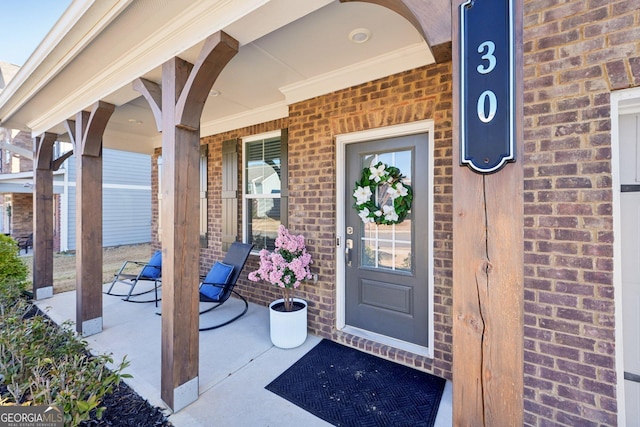 view of exterior entry featuring covered porch and brick siding