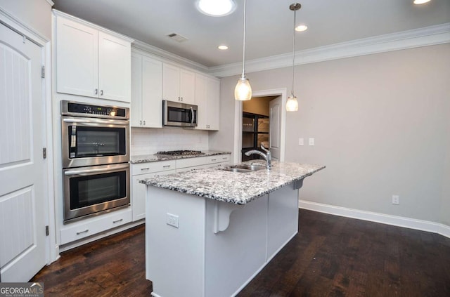 kitchen with dark wood-style flooring, decorative backsplash, appliances with stainless steel finishes, white cabinets, and a sink