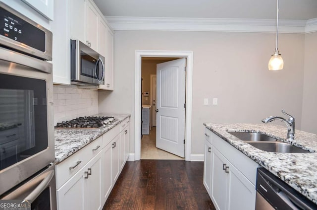 kitchen with stainless steel appliances, a sink, ornamental molding, decorative backsplash, and dark wood-style floors