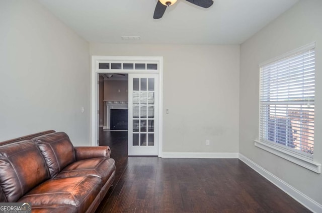 unfurnished living room featuring baseboards, visible vents, a ceiling fan, dark wood-style floors, and a fireplace