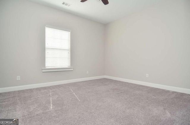 carpeted empty room featuring ceiling fan, visible vents, and baseboards