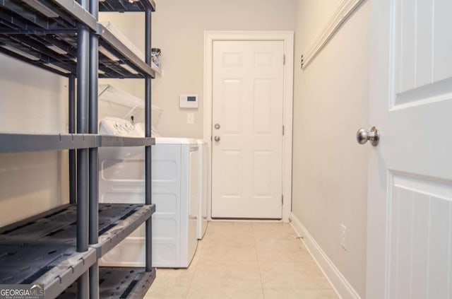 laundry room featuring laundry area, baseboards, separate washer and dryer, and light tile patterned flooring