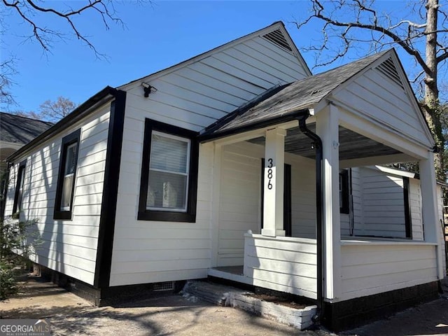 view of side of home with covered porch and roof with shingles