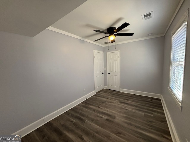 spare room featuring dark wood-style floors, visible vents, crown molding, and baseboards