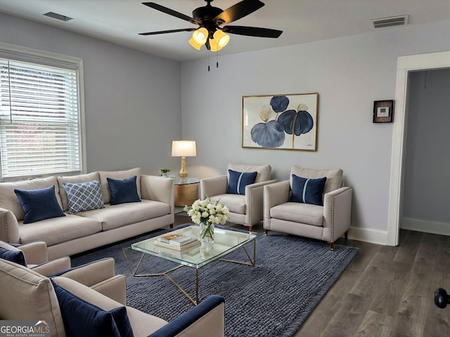 living room with a ceiling fan, visible vents, baseboards, and wood finished floors