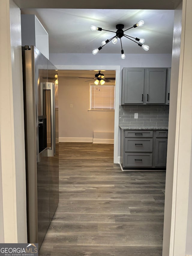 kitchen with stainless steel fridge, baseboards, dark wood-type flooring, gray cabinets, and backsplash