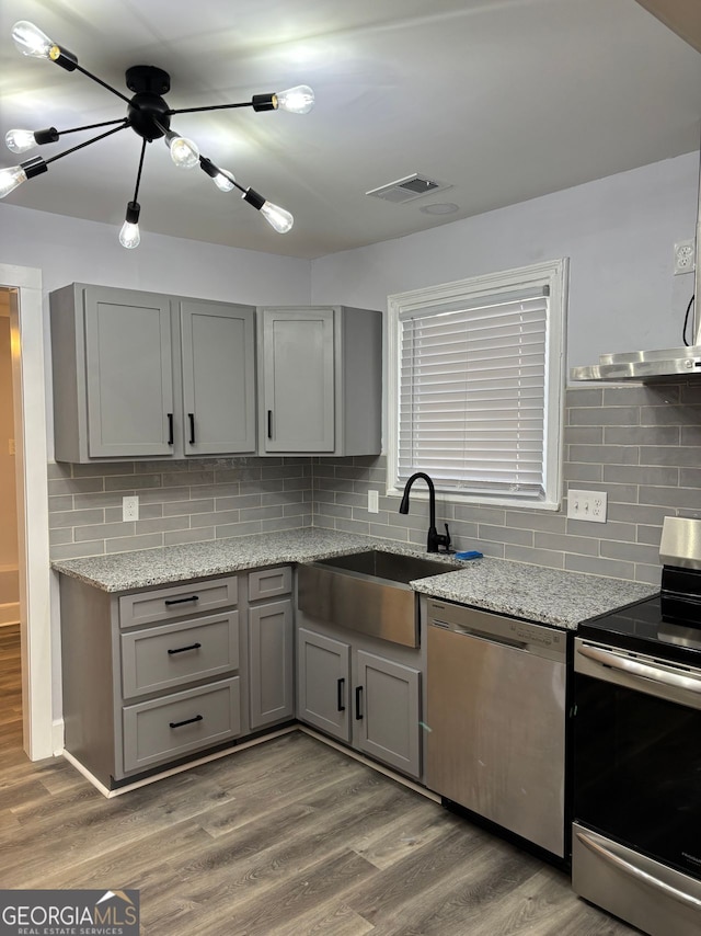 kitchen featuring light wood-style flooring, gray cabinets, stainless steel appliances, and a sink