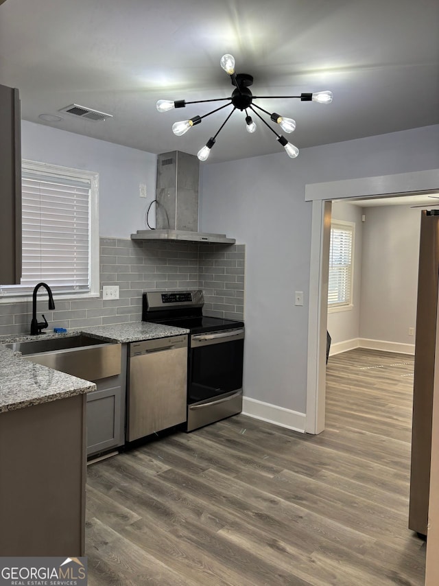 kitchen with visible vents, dark wood finished floors, wall chimney exhaust hood, stainless steel appliances, and a sink