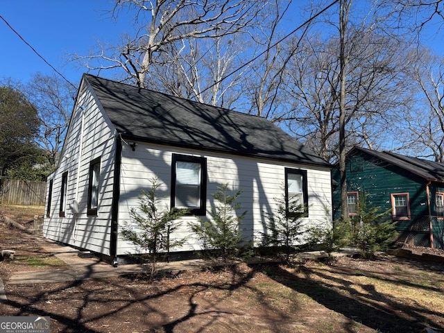 exterior space featuring a shingled roof and fence