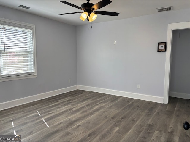 unfurnished room featuring dark wood-type flooring, visible vents, baseboards, and a ceiling fan