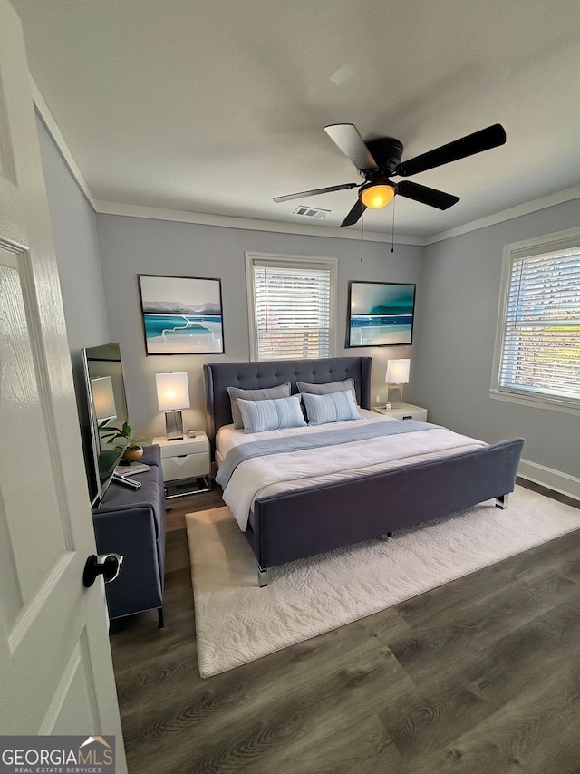 bedroom with multiple windows, visible vents, crown molding, and wood finished floors