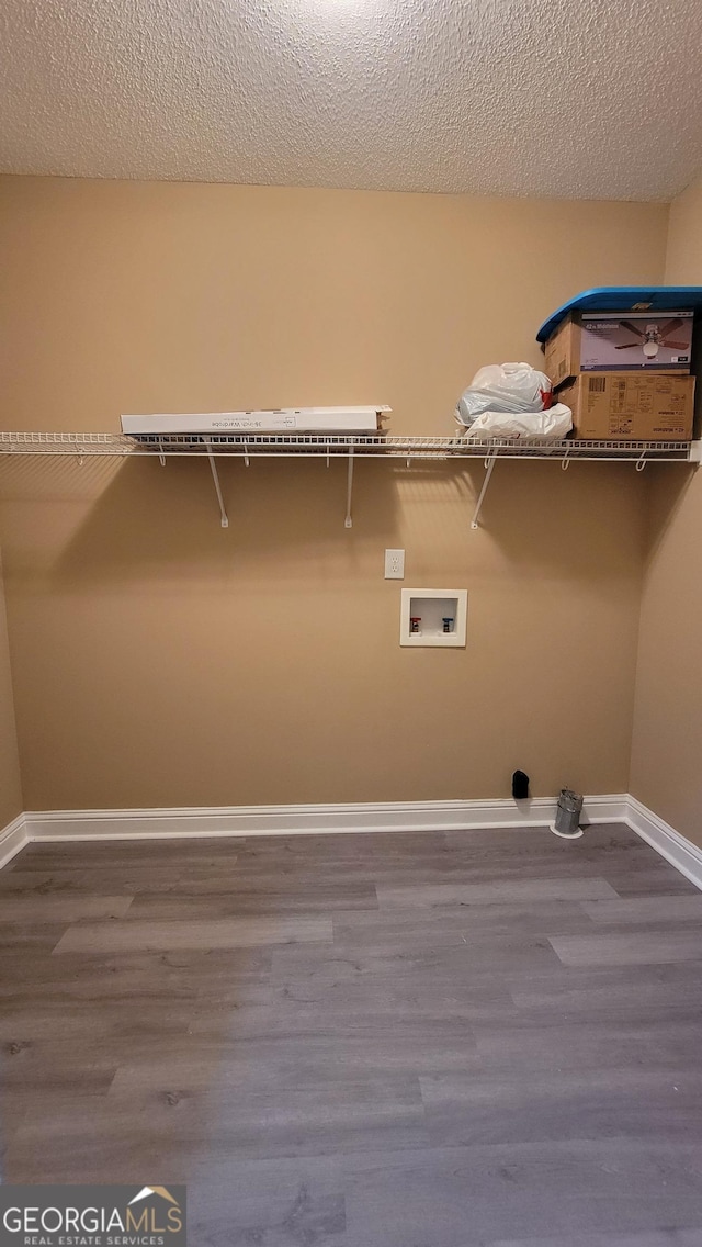 laundry room featuring a textured ceiling, washer hookup, wood finished floors, and baseboards