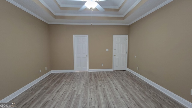 unfurnished room featuring wood finished floors, a ceiling fan, baseboards, ornamental molding, and a raised ceiling