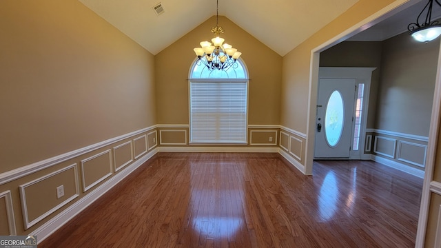 entryway with visible vents, dark wood-style flooring, vaulted ceiling, a chandelier, and a decorative wall