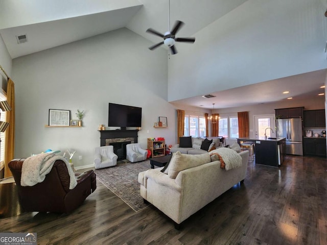 living room featuring a stone fireplace, dark wood-style flooring, and visible vents